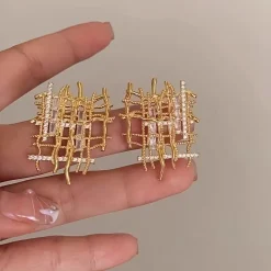 Ζευγάρι χρυσών καρφωτών σκουλαρικιών με αφηρημένο δικτυωτό ή πλεκτό σχέδιο, διακοσμημένα με λαμπερά κρύσταλλα Zircon σε κοπή μπαγκέτας και στρογγυλή. Σκουλαρίκια statement.