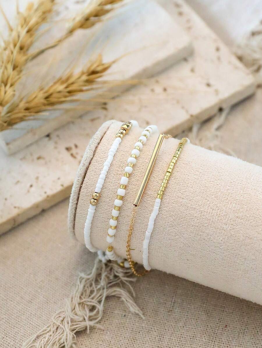 Σετ 4 Γυναικεία Βραχιόλια με Λευκές Χάντρες και Χρυσή Μπάρα