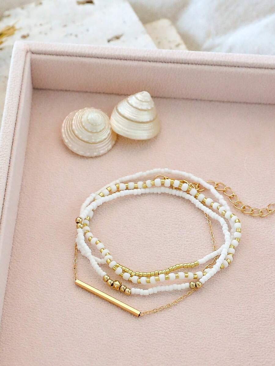 Σετ 4 Γυναικεία Βραχιόλια με Λευκές Χάντρες και Χρυσή Μπάρα
