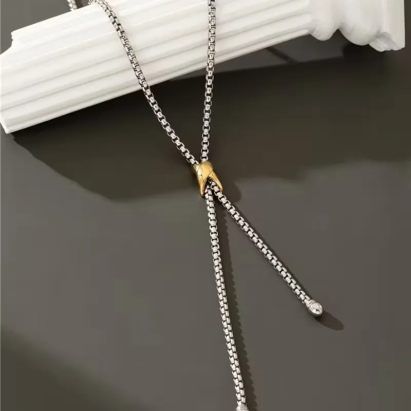 Ασημί κολιέ γραβάτα με χρυσή λεπτομέρεια φορεμένο με κομψό λευκό σακάκι.