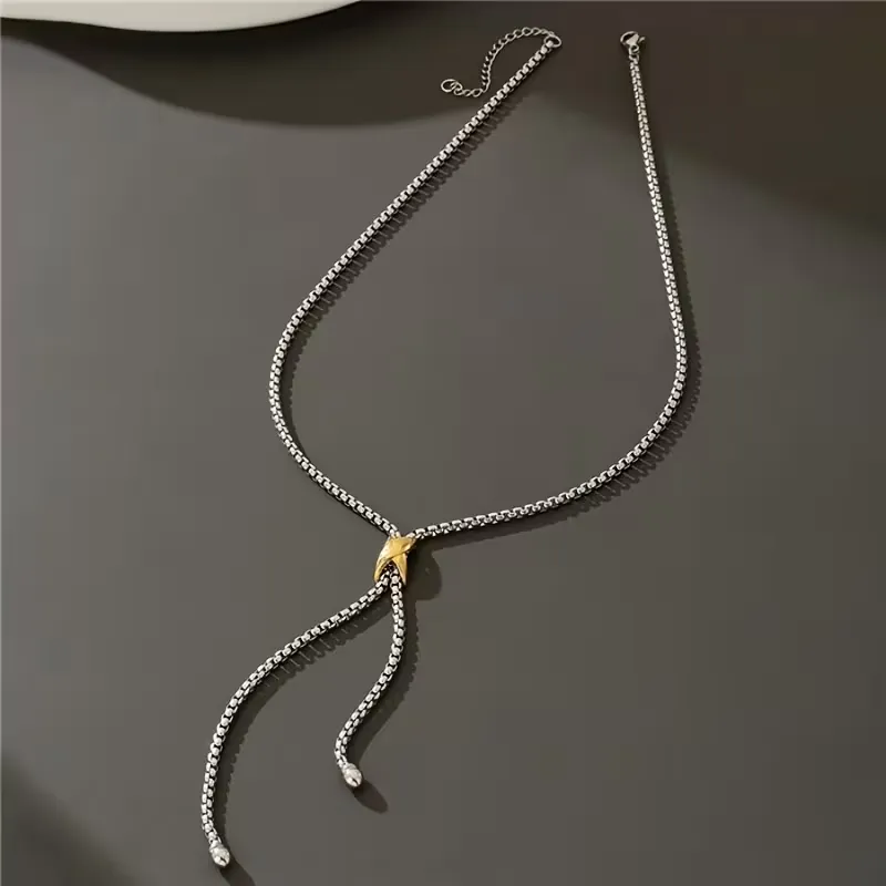 Ασημί κολιέ γραβάτα με χρυσή λεπτομέρεια φορεμένο με κομψό λευκό σακάκι.