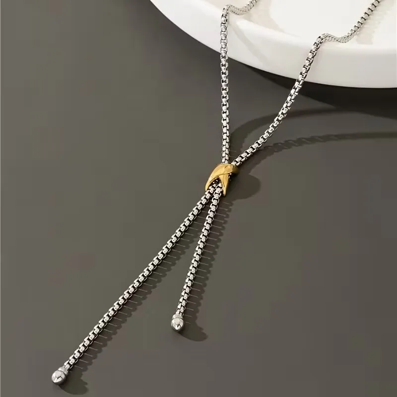 Ασημί κολιέ γραβάτα με χρυσή λεπτομέρεια φορεμένο με κομψό λευκό σακάκι.