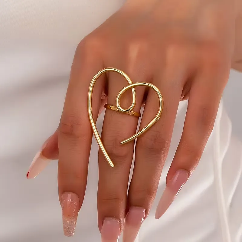 Χρυσό δαχτυλίδι καρδιά σε μοντέρνο σχέδιο φορεμένο σε γυναικείο χέρι.