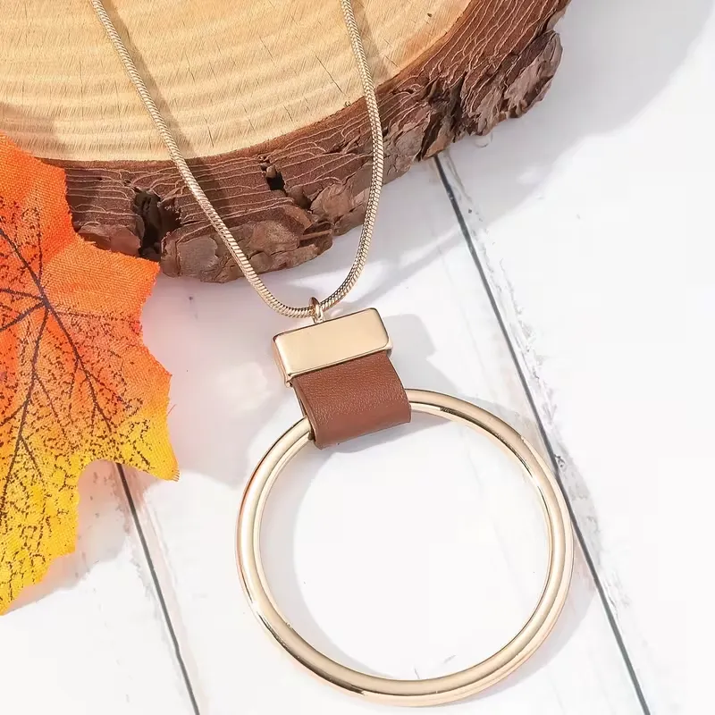 Γυναικείο μακρύ κολιέ με χρυσό γεωμετρικό κύκλο και δερμάτινη λεπτομέρεια