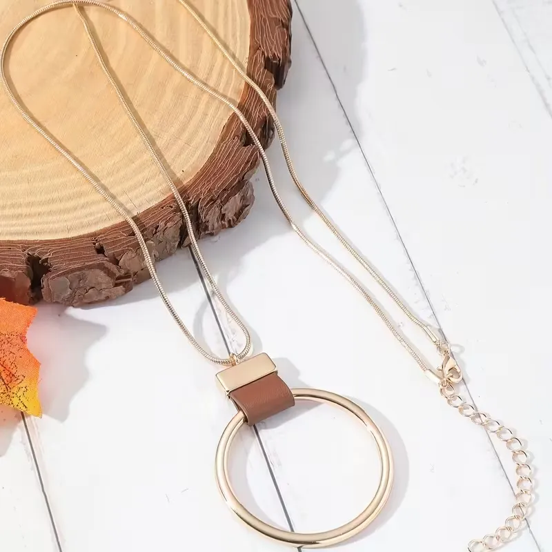 Γυναικείο μακρύ κολιέ με χρυσό γεωμετρικό κύκλο και δερμάτινη λεπτομέρεια