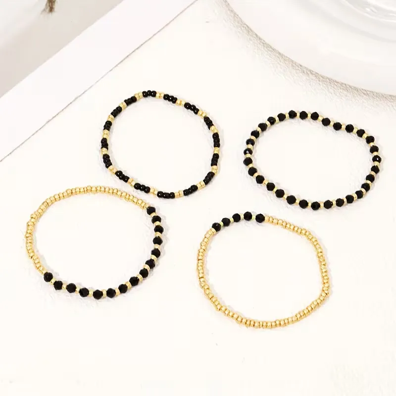 Γυναικείο σετ βραχιόλια με χρυσές χάντρες και μαύρους κρυστάλλους σε λευκό φόντο.