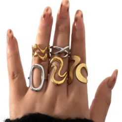 Γυναικείο χέρι που φοράει minimal δαχτυλίδια με γεωμετρικά σχέδια σε χρυσό και ασήμι.