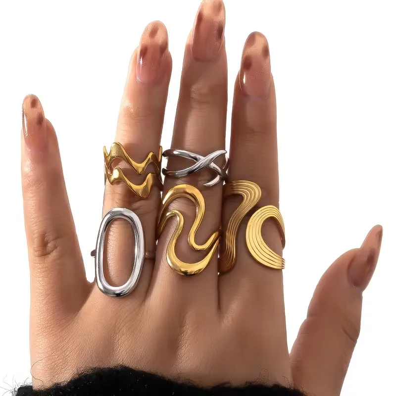 Γυναικείο χέρι που φοράει minimal δαχτυλίδια με γεωμετρικά σχέδια σε χρυσό και ασήμι.