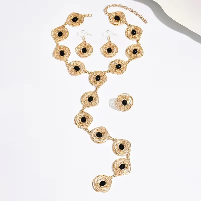 Γυναικείο σετ κοσμημάτων με χρυσό κολιέ, σκουλαρίκια και δαχτυλίδι με μαύρες πέτρες.