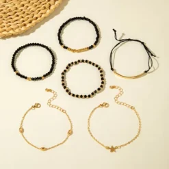 Γυναικείο σετ βραχιόλια 6 τεμαχίων με μαύρες χάντρες, χρυσές αλυσίδες και charm αστέρι.
