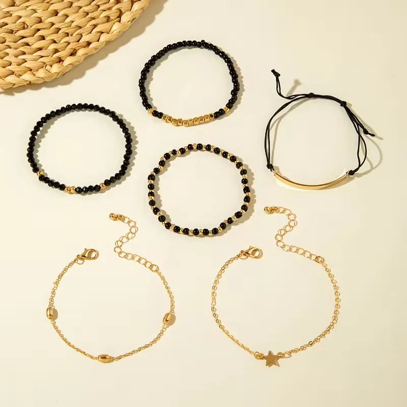 Γυναικείο σετ βραχιόλια 6 τεμαχίων με μαύρες χάντρες, χρυσές αλυσίδες και charm αστέρι.