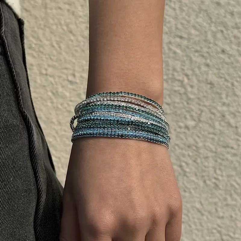 Πολλαπλά ελαστικά βραχιόλια ριβιέρα με πολύχρωμα ζιργκόν φορεμένα στον καρπό για layering.