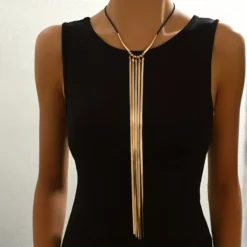 Μακρύ γυναικείο κολιέ με τέσσερις χρυσές αλυσίδες φίδι και μαύρο κορδόνι σε μαύρο φόρεμα.