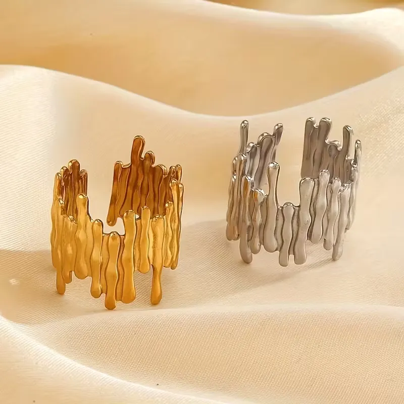 σετ Γυναικείο δαχτυλίδι σε χρυσό και ασημί χρώμα με ακανόνιστο, ρευστό σχέδιο πάνω σε ύφασμα.