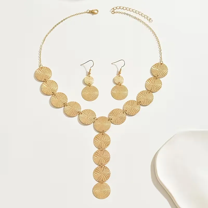 Χρυσό σετ κοσμημάτων με κολιέ και σκουλαρίκια από ανάγλυφους κυκλικούς δίσκους φορεμένο σε μοντέλο.