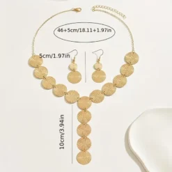 Χρυσό σετ κοσμημάτων με κολιέ και σκουλαρίκια από ανάγλυφους κυκλικούς δίσκους φορεμένο σε μοντέλο.