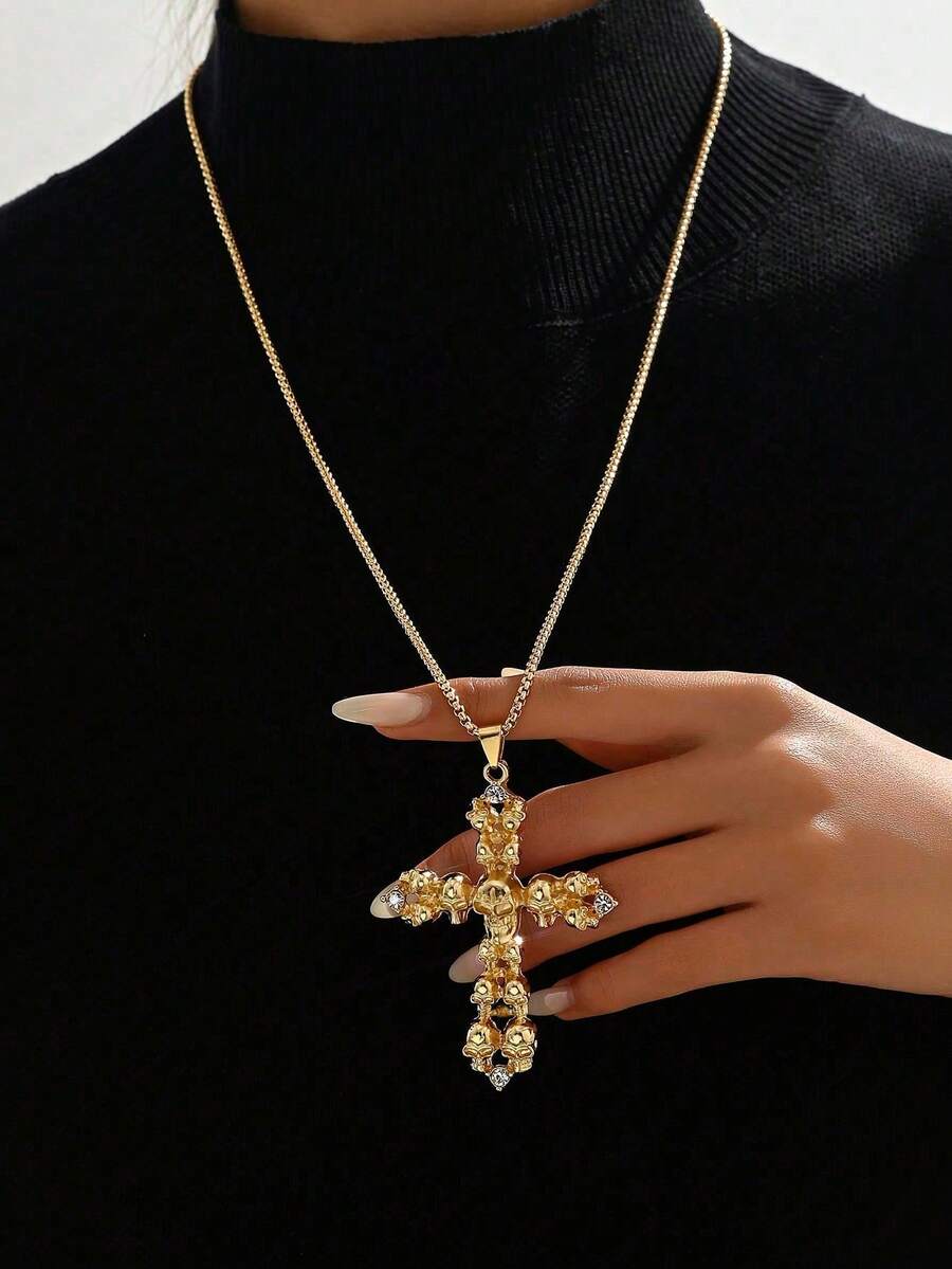 κολιέ με χρυσό σταυρό και λεπτομέρειες από νεκροκεφαλές σε μαύρο φόντο.