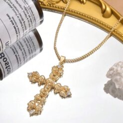 κολιέ με χρυσό σταυρό και λεπτομέρειες από νεκροκεφαλές σε μαύρο φόντο.