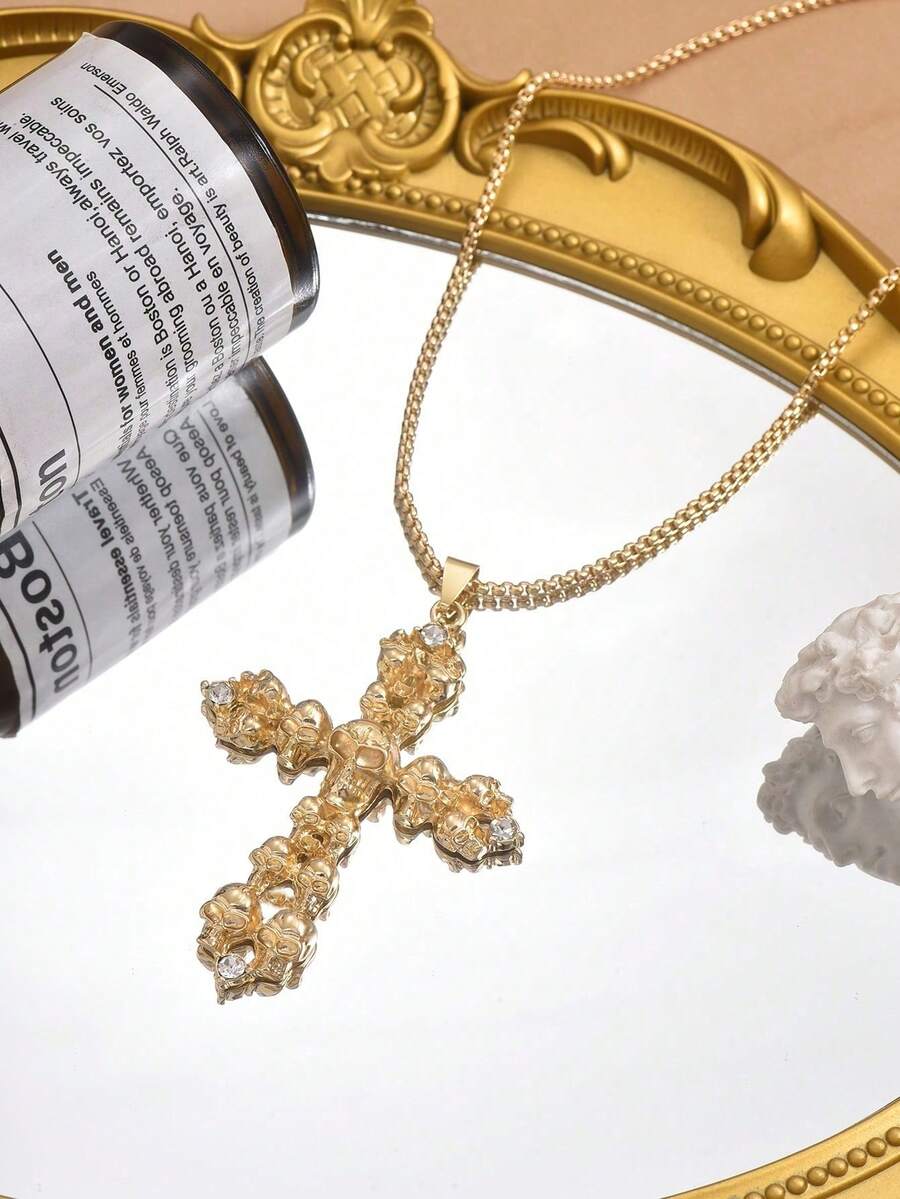 κολιέ με χρυσό σταυρό και λεπτομέρειες από νεκροκεφαλές σε μαύρο φόντο.