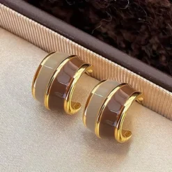 Γυναικεία χρυσά σκουλαρίκια κρίκοι με δίχρωμο σμάλτο σε καφέ και μπεζ αποχρώσεις.