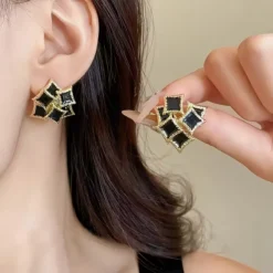 Vintage γυναικεία σκουλαρίκια με μαύρο σμάλτο και ανάγλυφο χρυσό πλαίσιο.