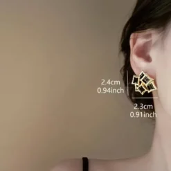 Vintage γυναικεία σκουλαρίκια με μαύρο σμάλτο και ανάγλυφο χρυσό πλαίσιο.