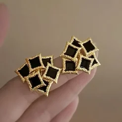 Vintage γυναικεία σκουλαρίκια με μαύρο σμάλτο και ανάγλυφο χρυσό πλαίσιο.