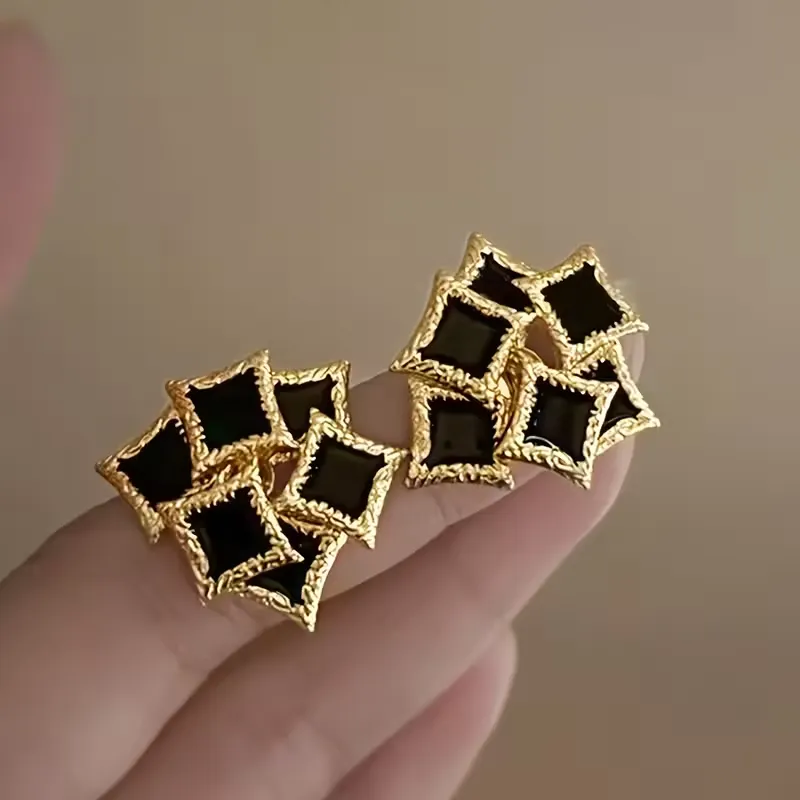 Vintage γυναικεία σκουλαρίκια με μαύρο σμάλτο και ανάγλυφο χρυσό πλαίσιο.