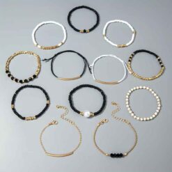 Γυναικείο σετ 12 βραχιόλια με μαύρες λευκές χάντρες πέρλα και χρυσές αλυσίδες σε λευκό φόντο.