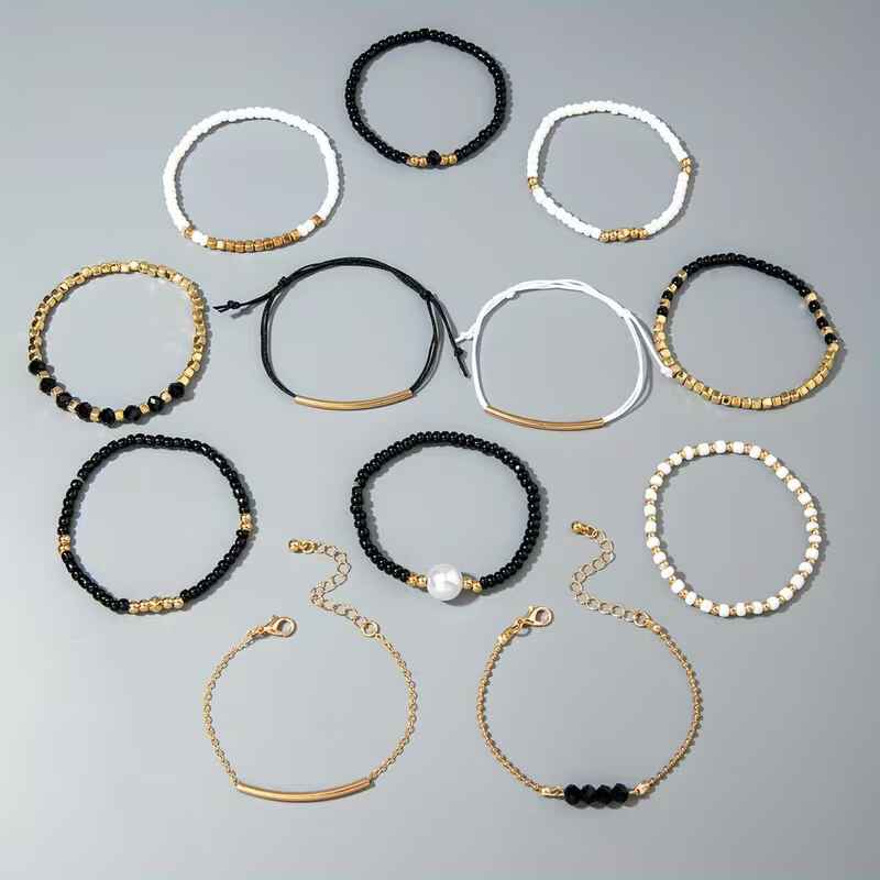 Γυναικείο σετ 12 βραχιόλια με μαύρες λευκές χάντρες πέρλα και χρυσές αλυσίδες σε λευκό φόντο.