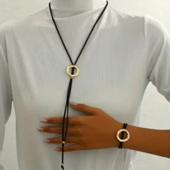 Γυναικείο σετ κολιέ λάσο και βραχιόλι με μαύρο κορδόνι και σφυρήλατους χρυσούς κύκλους.