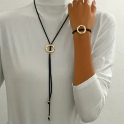 Γυναικείο σετ κολιέ λάσο και βραχιόλι με μαύρο κορδόνι και σφυρήλατους χρυσούς κύκλους.