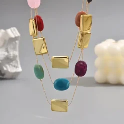 Γυναικείο τριπλό κολιέ layered με πολύχρωμες πέτρες και χρυσά γεωμετρικά στοιχεία.
