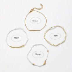 Σετ τεσσάρων γυναικείων βραχιολιών με λευκές χάντρες και χρυσή μεταλλική μπάρα, σε bohemian στυλ.