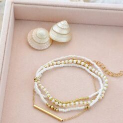 Σετ τεσσάρων γυναικείων βραχιολιών με λευκές χάντρες και χρυσή μεταλλική μπάρα, σε bohemian στυλ.