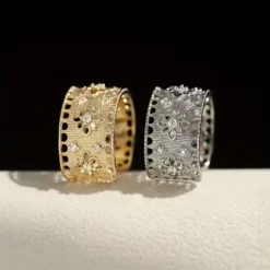 Φαρδύ ανοιγόμενο δαχτυλίδι με διάτρητο σχέδιο δαντέλας, ανάγλυφα λουλούδια και πέτρες ζιργκόν σε χρυσό και ασημί χρώμα.