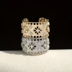 Φαρδύ ανοιγόμενο δαχτυλίδι με διάτρητο σχέδιο δαντέλας, ανάγλυφα λουλούδια και πέτρες ζιργκόν σε χρυσό και ασημί χρώμα.