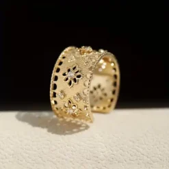 Φαρδύ ανοιγόμενο δαχτυλίδι με διάτρητο σχέδιο δαντέλας, ανάγλυφα λουλούδια και πέτρες ζιργκόν σε χρυσό και ασημί χρώμα.