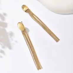 Χρυσά μακριά σκουλαρίκια με οβάλ βάση και πέντε κρεμαστές αλυσίδες τύπου snake chain σε λευκό φόντο.