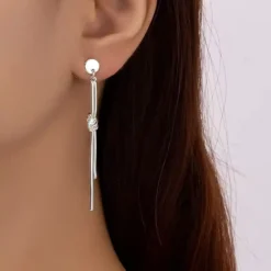 Ζευγάρι μακριά minimal σκουλαρίκια με μεταλλικό κόμπο και γραμμική ράβδο σε ασημί χρώμα.