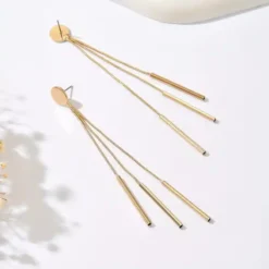 Γυναικεία μακριά χρυσά και ασημένια σκουλαρίκια με τρεις κρεμαστές αλυσίδες και μεταλλικά στοιχεία bars σε λευκό φόντο.