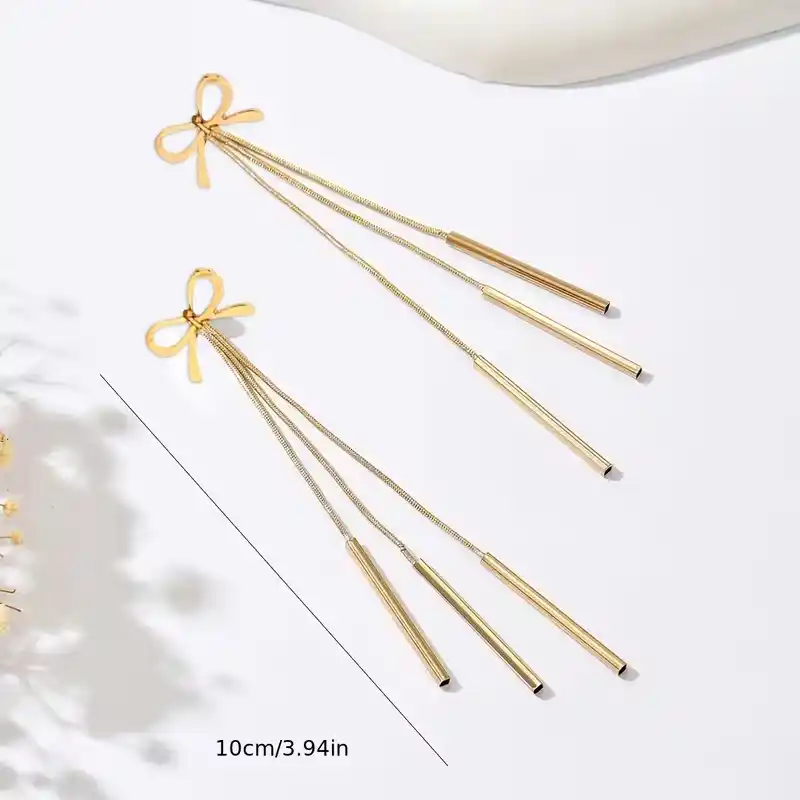 Χρυσά μακριά σκουλαρίκια 10 εκατοστών με σχέδιο φιόγκο και τρεις κρεμαστές λεπτές μπάρες σε λευκό φόντο.