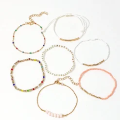 Σετ από επτά γυναικεία βραχιόλια σε boho στυλ με πολύχρωμες χάντρες, χρυσές αλυσίδες και λευκό κορδόνι