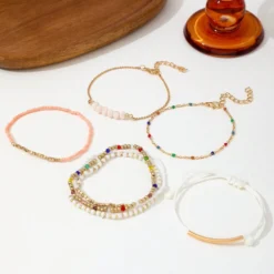 Σετ από επτά γυναικεία βραχιόλια σε boho στυλ με πολύχρωμες χάντρες, χρυσές αλυσίδες και λευκό κορδόνι