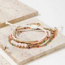 Σετ από επτά γυναικεία βραχιόλια σε boho στυλ με πολύχρωμες χάντρες, χρυσές αλυσίδες και λευκό κορδόνι