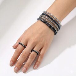 Σετ με πέντε ελαστικά βραχιόλια και δύο δαχτυλίδια από κρυστάλλινες χάντρες σε γκρι, μπλε και χρυσές αποχρώσεις.