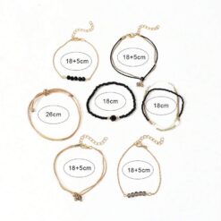 Σετ οκτώ γυναικεία βραχιόλια με μαύρες χάντρες, κρύσταλλα και χρυσά στοιχεία σε boho στυλ.