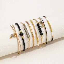 Σετ οκτώ γυναικεία βραχιόλια με μαύρες χάντρες, κρύσταλλα και χρυσά στοιχεία σε boho στυλ.