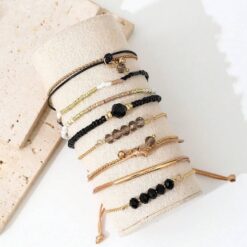 Σετ οκτώ γυναικεία βραχιόλια με μαύρες χάντρες, κρύσταλλα και χρυσά στοιχεία σε boho στυλ.
