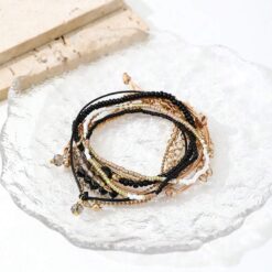 Σετ οκτώ γυναικεία βραχιόλια με μαύρες χάντρες, κρύσταλλα και χρυσά στοιχεία σε boho στυλ.